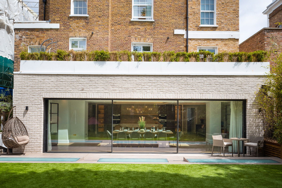 Completed rear house extension with broad glazing beneath the existing brick elevation